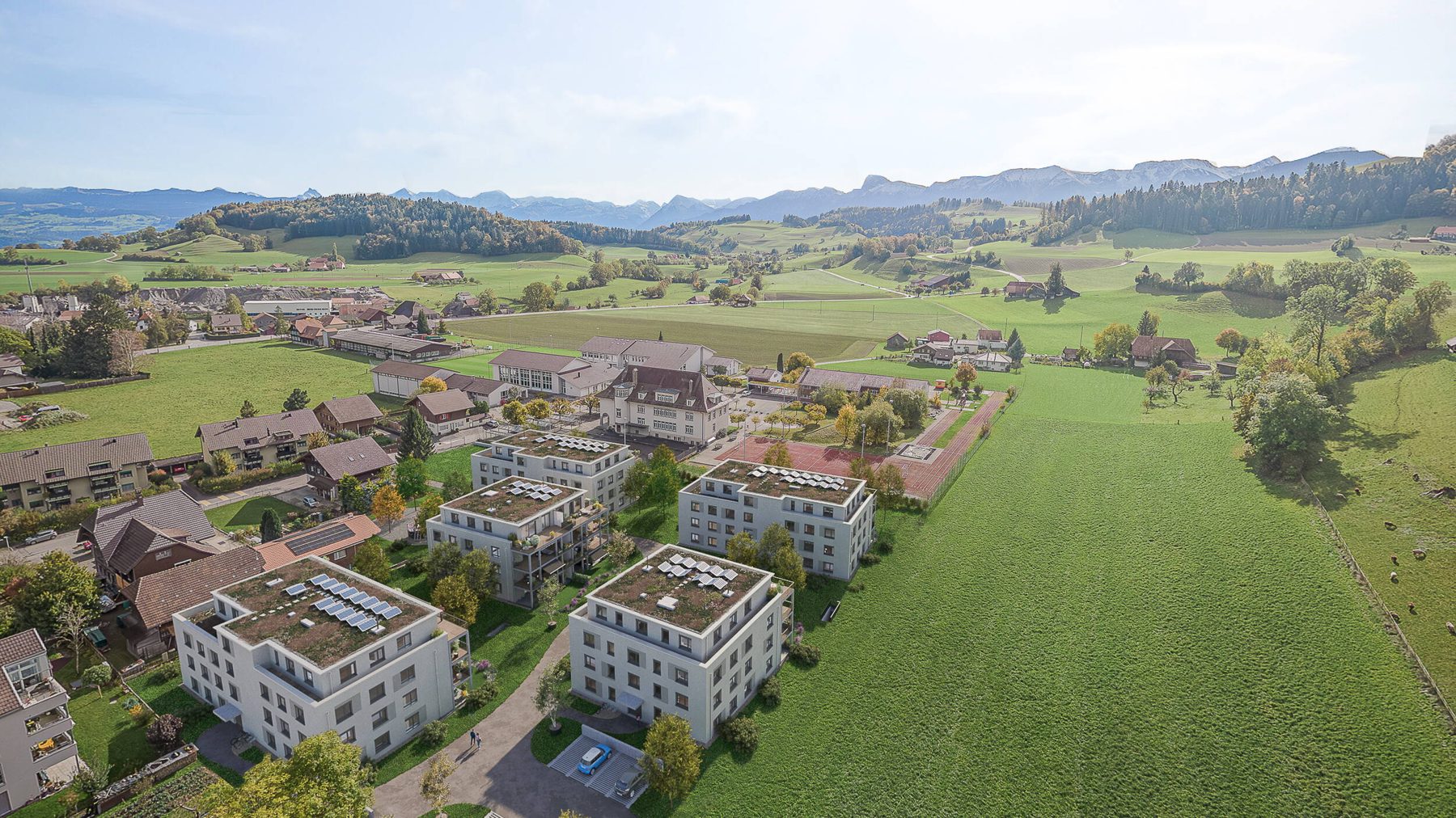 Luftbild der fünf Häuser des Dorfparks vor den Voralpen